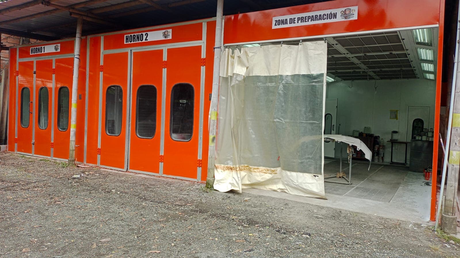 Fila de cabinas de pintura naranja junto a la zona de preparación