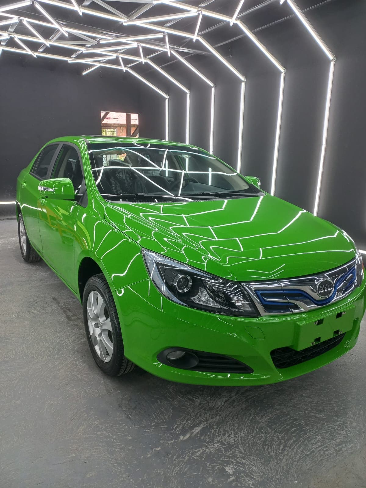 Sedán verde bajo las luces LED hexagonales del túnel del taller