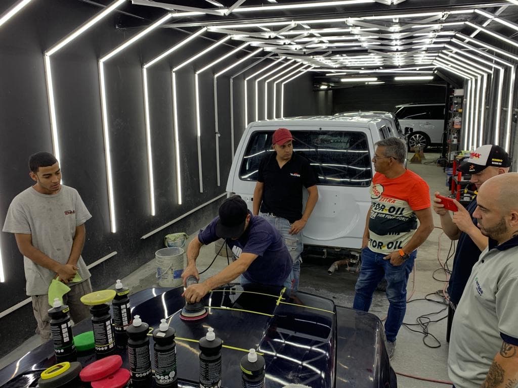 Pulido del capó de un vehículo en el túnel de luces del taller