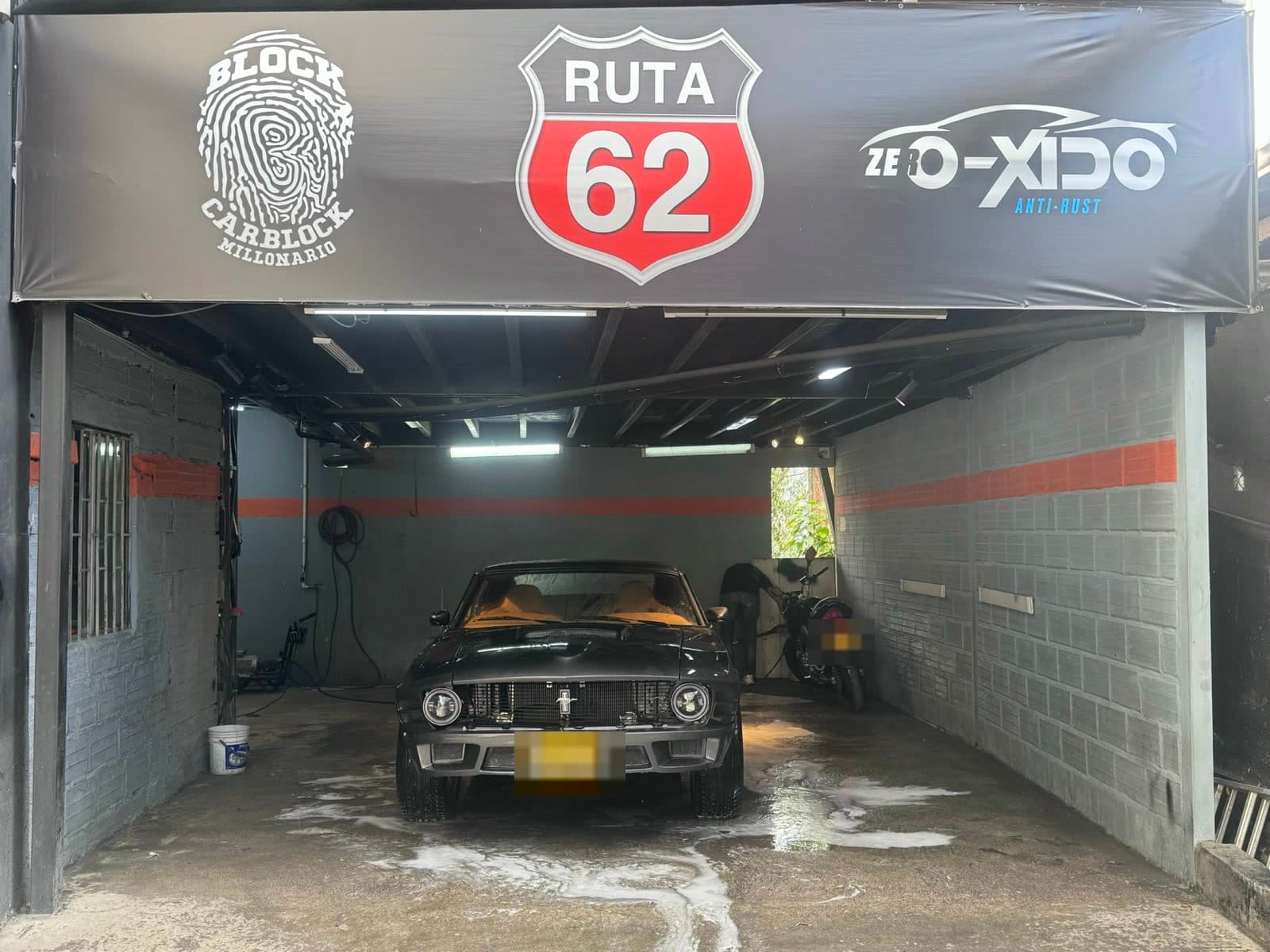 Fachada del taller Ruta 62 con un Ford Mustang clásico en la entrada